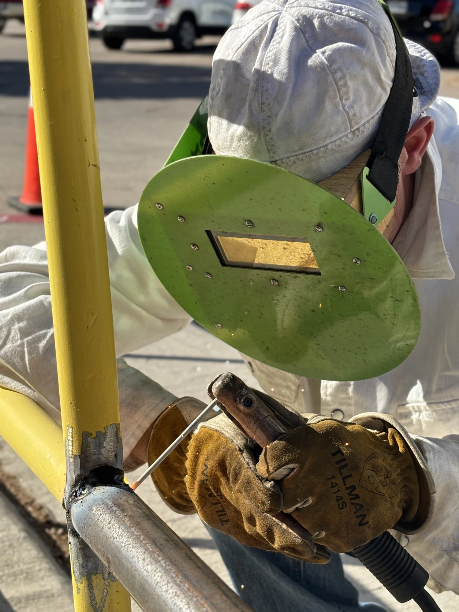 Welder stick-welding a yellow steel rail during an on-site repair